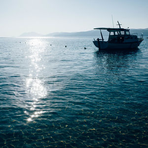 Boat sailing in sea against sky during sunny day