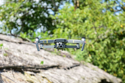 Eye-level view of drone flying against trees