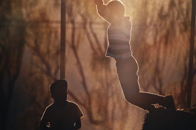 Boys playing in field during sunset