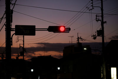 Low angle view of road signal against sky at sunset