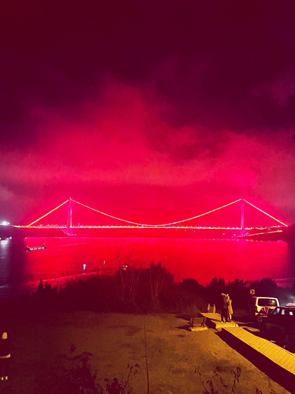 LOW ANGLE VIEW OF ILLUMINATED SUSPENSION BRIDGE AGAINST SKY DURING SUNSET