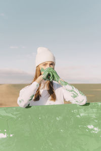 Young woman with green hands, leaning on painting