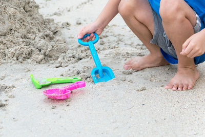 Low section of boy playing with toys on sand