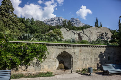 Arch bridge amidst trees and buildings against sky