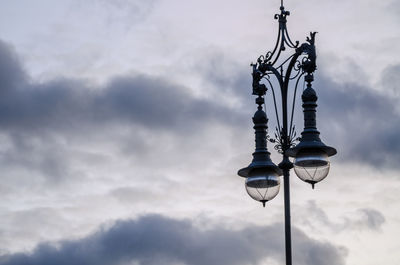 Low angle view of street lamp against cloudy sky