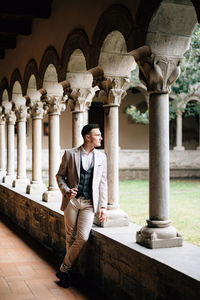 Full length of young man sitting outside historic building