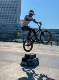 Man riding bicycle in city against sky