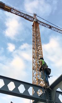 Low angle view of crane at construction site against sky