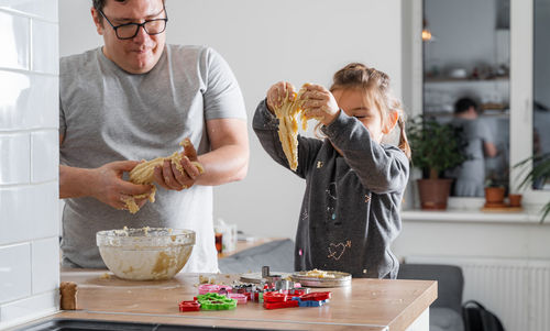 Father feeling playful with his caucasian little daughter, while preparing homemade dough 