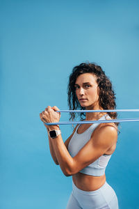 Portrait of woman exercising against blue background