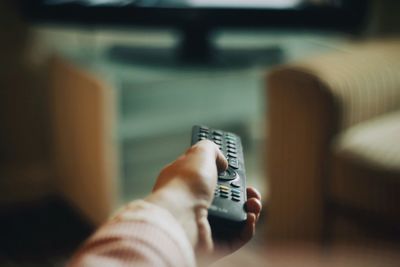 Cropped hand of woman holding remote control