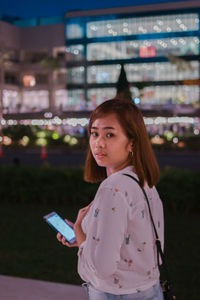 Portrait of woman standing in city at night