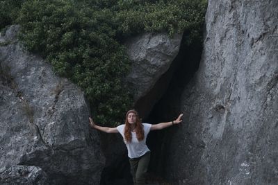 Young woman with eyes closed standing by cave