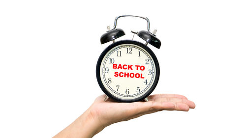 Close-up of hand holding clock over white background