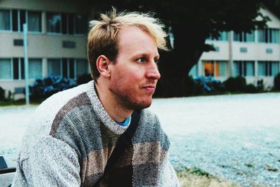 Close-up of blond mid adult man sitting in city