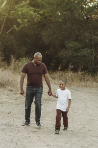 Happy father and son holding hands and walking in field