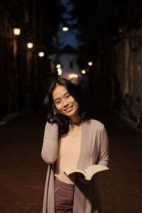 Portrait of smiling woman standing at night