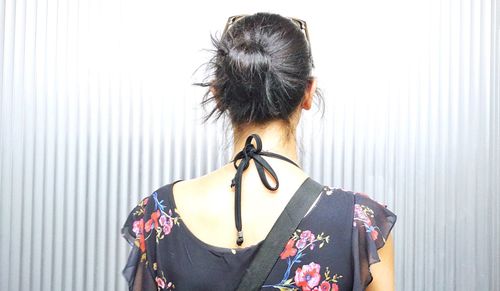 Rear view of woman standing against wall