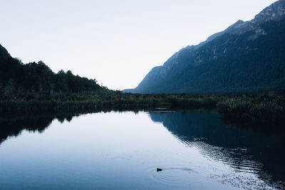 Scenic view of lake by mountains against clear sky