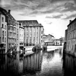 Canal in city against sky