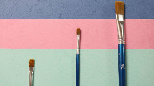 High angle view of paintbrushes on multi colored papers at table