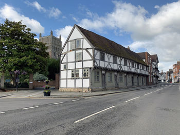 Road by buildings in city against sky