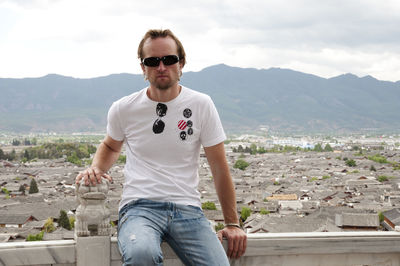 Portrait of man sitting against townscape