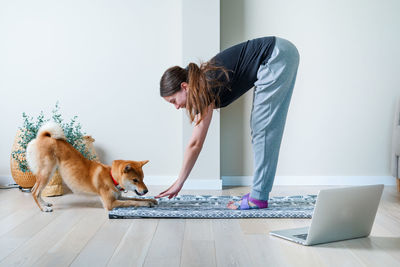 Woman is doing yoga with her dog. healthy lifestyle. doga or doga yoga. online yoga