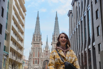 Happy millenial woman in a yellow coat in european city 