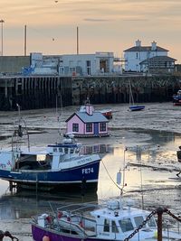 View of fishing boats moored at harbor during sunset