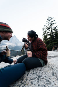 Young couple enjoys a time in wilderness taking selfies laughing and having fun with their cat