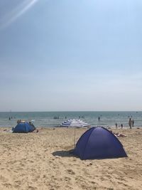 Deck chairs on beach against sky