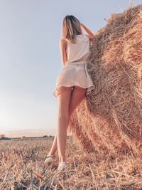 Low angle view of woman standing by hay against sky