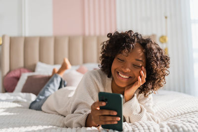 Young woman using mobile phone while sitting at home