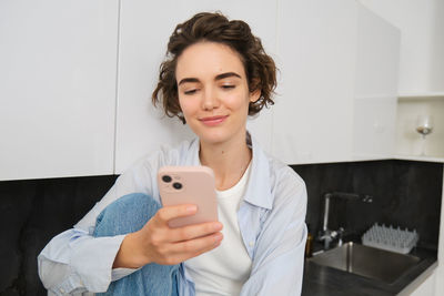 Portrait of young woman using mobile phone at home