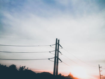 Low angle view of silhouette electricity pylon against sky during sunset