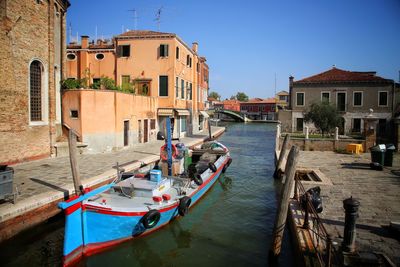 Buildings by canal against clear sky in city