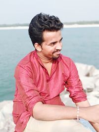 Man sitting on retaining wall by sea