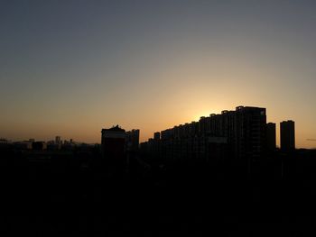 Silhouette buildings against sky during sunset