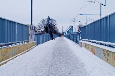 Snow covered walkway against sky during winter