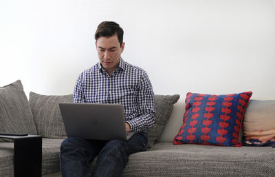 Man using laptop while sitting on sofa at home