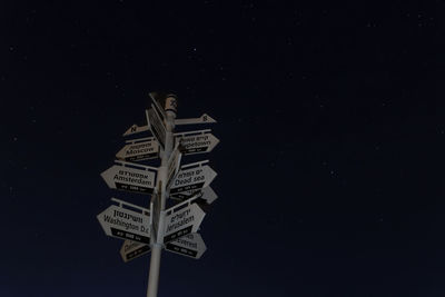 Low angle view of information sign against sky at night