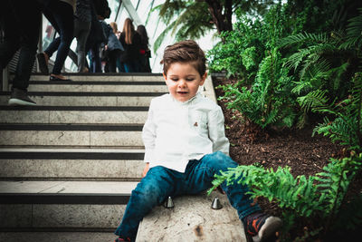 Boy looking away while sitting on staircase