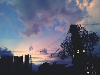 Low angle view of power lines against cloudy sky