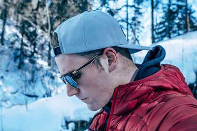 Side view of young man wearing cap and sunglasses during winter