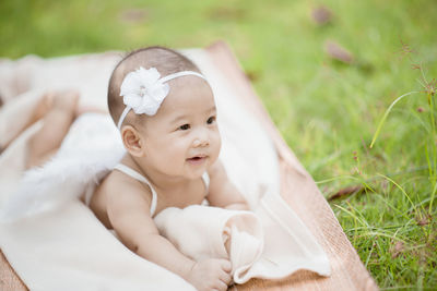 Cute baby girl wearing costume wing while lying on blanket