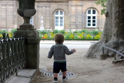 Rear view of boy standing on footpath