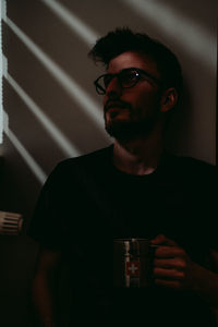 Young man having coffee and enjoying sunbeam through curtains.