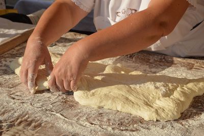 Midsection of woman kneading dough at kitchen counter