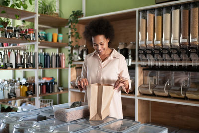 Happy black female checking groceries in paper bag